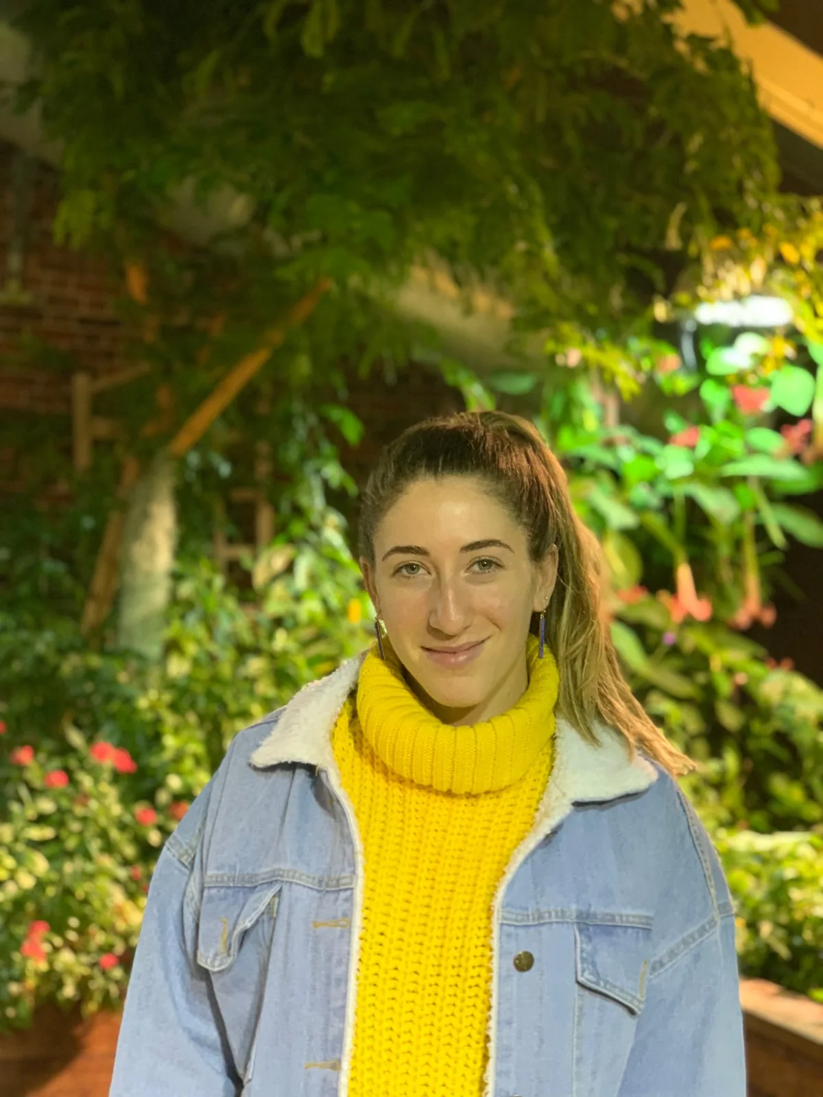 Jen in a yellow turtleneck, in a garden at night